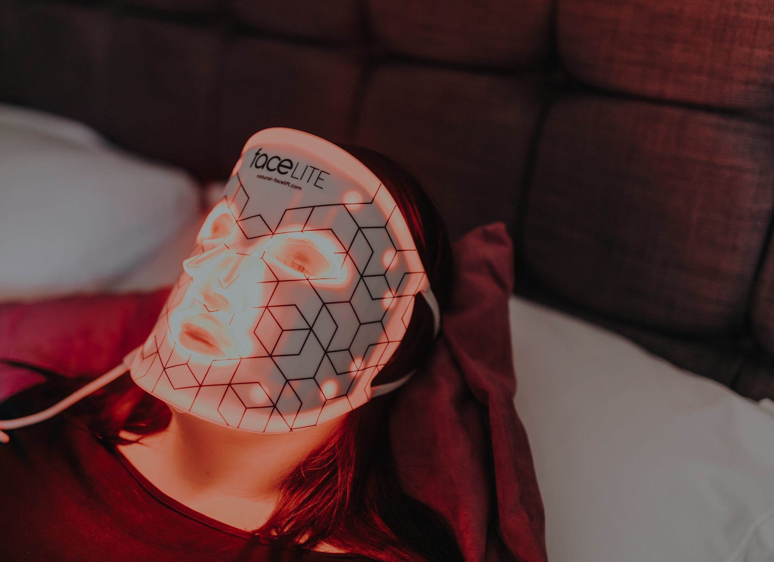 Person wearing a LED face mask with geometric design on a blurred background