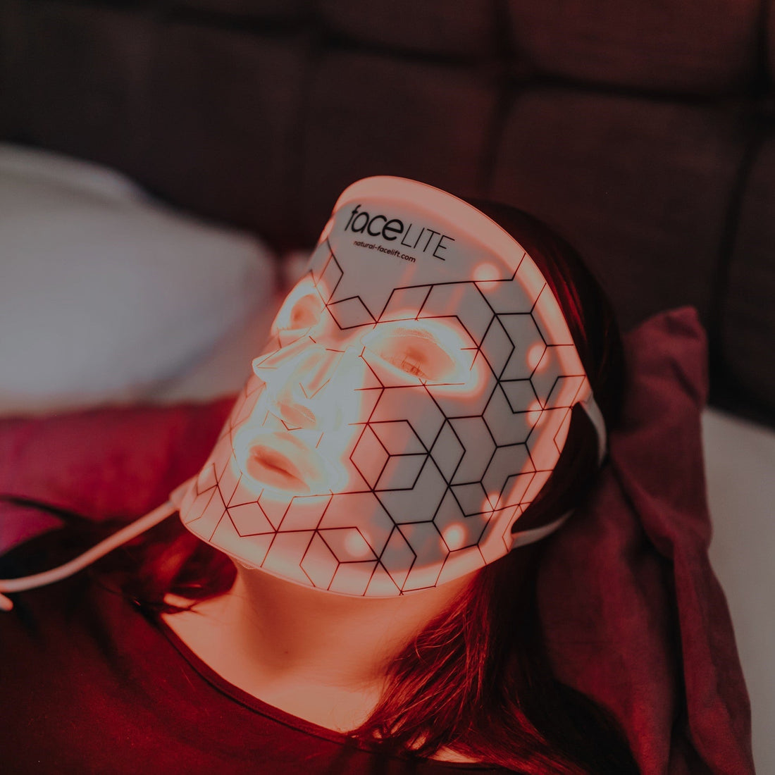 Person wearing a LED face mask with geometric design, brand 'faceLITE' visible.